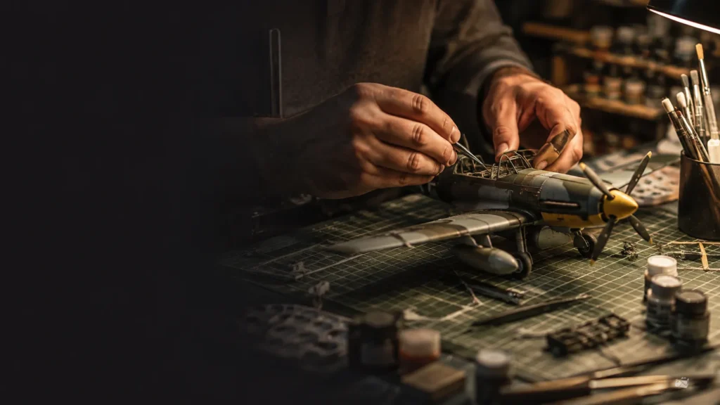 Modelbouwer werkt met precisiegereedschap aan een gedetailleerd schaalmodel van een vliegtuig.